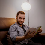 Smart Lâmpada Wi-Fi iluminando a sala enquanto homem lê seu livro