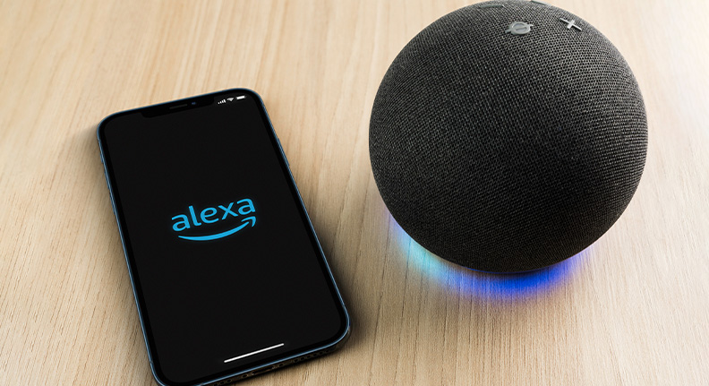 aplicativo da Alexa aberto em um celular ao lado de um speaker