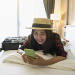 menina-feliz-usando-smartphone-em-quarto-de-hotel