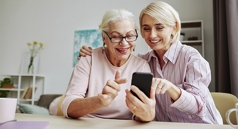 mulher ensinando sua mãe idosa a mexer no celular