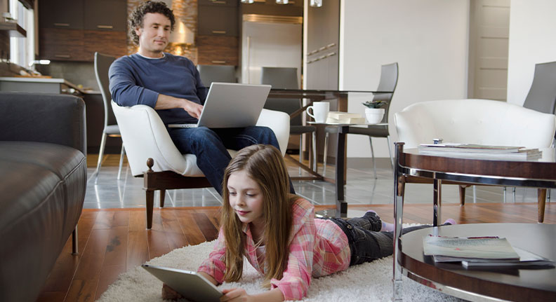 pai e filha usando a internet em seus dispositivos na sala