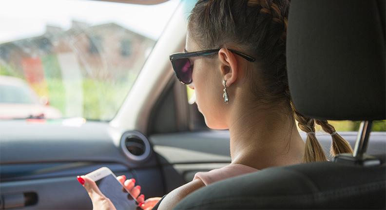 mulher viajando de carro usando o celular para checar as câmeras de segurança inteligentes de sua casa