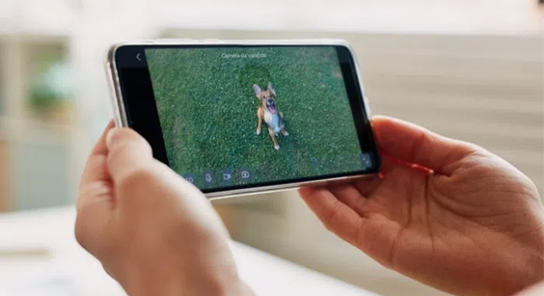 mulher monitorando seu cachorro com uma Smart Câmera Wi-Fi com Bateria da Positivo Casa Inteligente