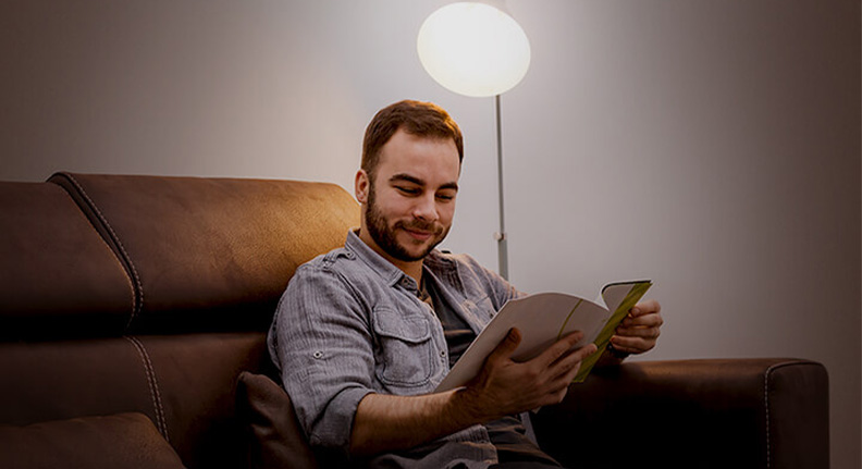 homem lendo com a iluminação de uma smart lâmpada da Positivo Casa Inteligente