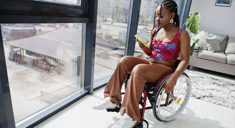 mulher em cadeira de rodas programando rotina pelo celular para seus dispositivos inteligentes