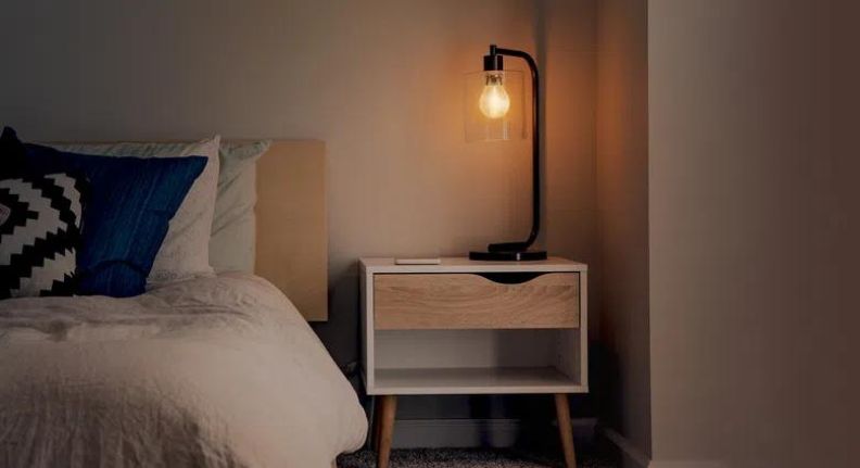 Smart Lâmpada Retrô da Positivo Casa Inteligente sendo usada em um abajur na mesa de cabeceira.